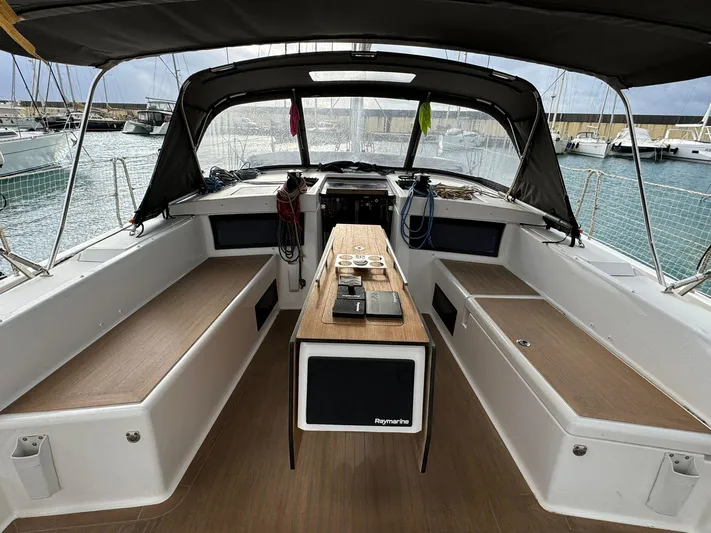  Yacht Photos Pics 2022 Dufour 470 yacht cockpit with seating, table, and navigation equipment in a marina setting.