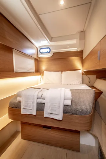 Lucky Fin Yacht Photos Pics Luxurious cabin interior of 2024 Bali CATSPACE yacht with cozy bed and elegant wood finish.