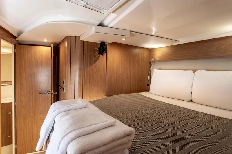 Lucky Fin Yacht Photos Pics Luxurious cabin interior of 2024 Bali CATSPACE yacht with cozy bed and wooden decor.