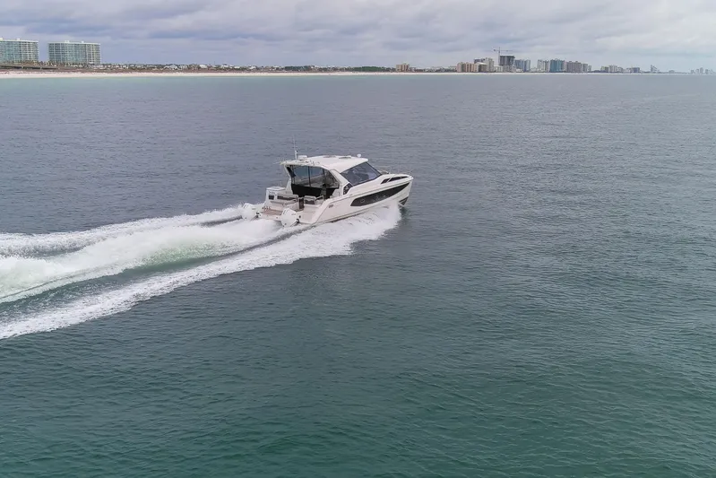  Yacht Photos Pics 2023 Aquila 36 Sport cruising on open water near a distant city skyline.