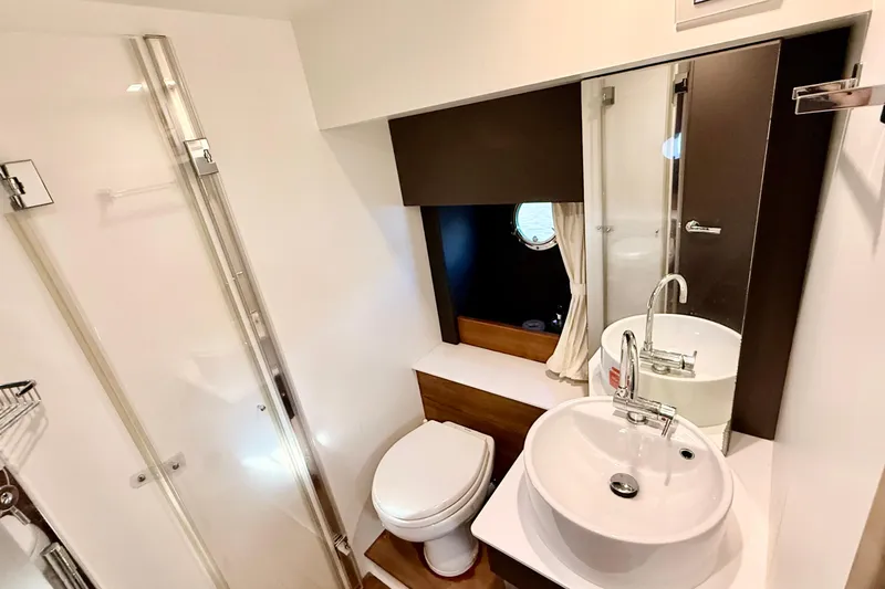  Yacht Photos Pics Modern bathroom in 2016 Cranchi M44 HT yacht, featuring sleek fixtures and a porthole window.