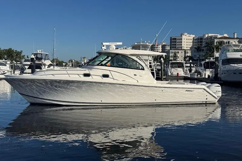  Yacht Photos Pics 2021 Pursuit OS 385 Offshore boat docked in marina, reflecting on calm water.