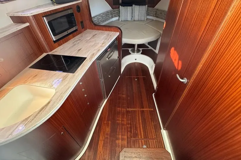  Yacht Photos Pics 2021 Pursuit OS 385 Offshore interior with kitchen and seating area.