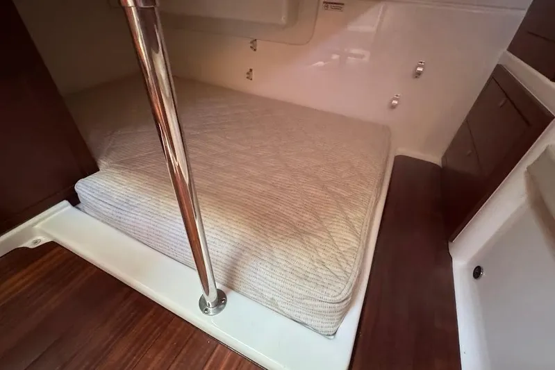  Yacht Photos Pics 2021 Pursuit OS 385 Offshore cabin interior with bed and wooden accents.