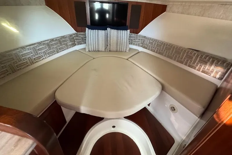  Yacht Photos Pics 2021 Pursuit OS 385 Offshore cabin interior with cushioned seating and patterned pillows.