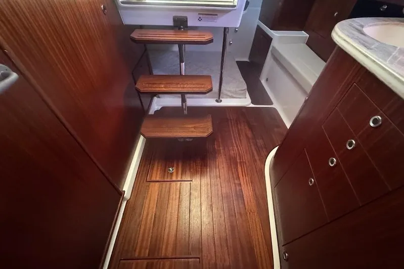  Yacht Photos Pics 2021 Pursuit OS 385 Offshore interior with wooden flooring and compact staircase.