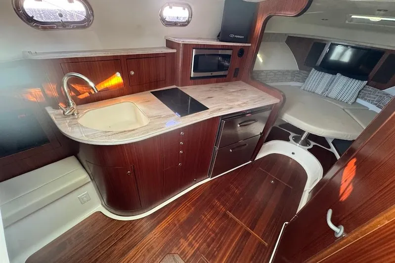  Yacht Photos Pics 2021 Pursuit OS 385 Offshore interior with kitchenette, sink, and seating area.