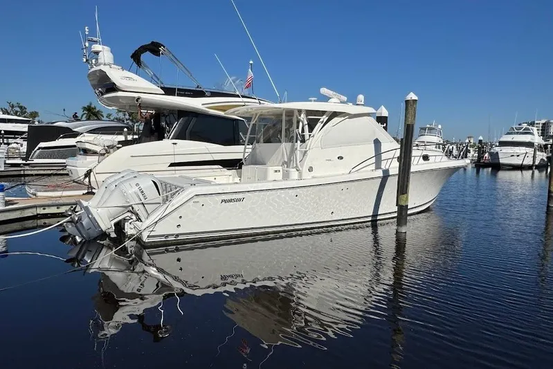  Yacht Photos Pics 2021 Pursuit OS 385 Offshore boat docked in a marina, reflecting on calm water.