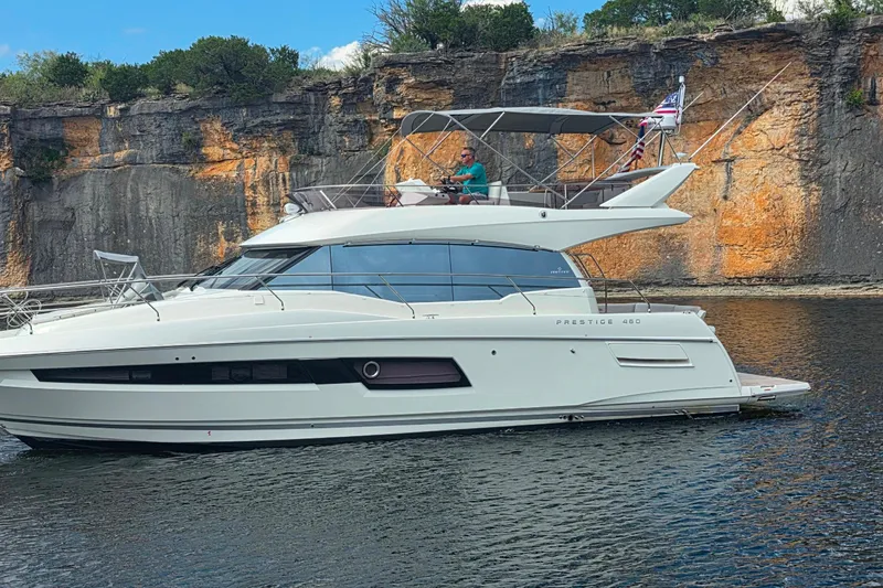 Im Your Huckelberry Yacht Photos Pics 2024 Prestige 460 yacht cruising near rocky cliffs on a sunny day.