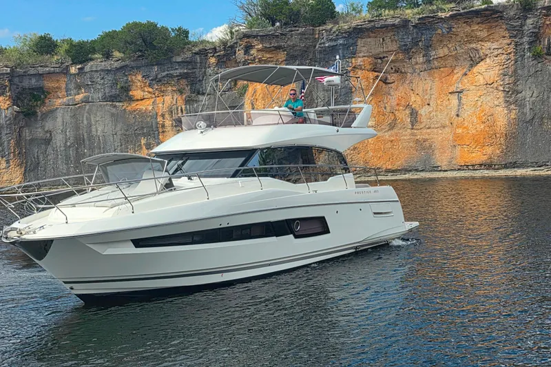 Im Your Huckelberry Yacht Photos Pics 2024 Prestige 460 yacht cruising near rocky cliffs on a sunny day.