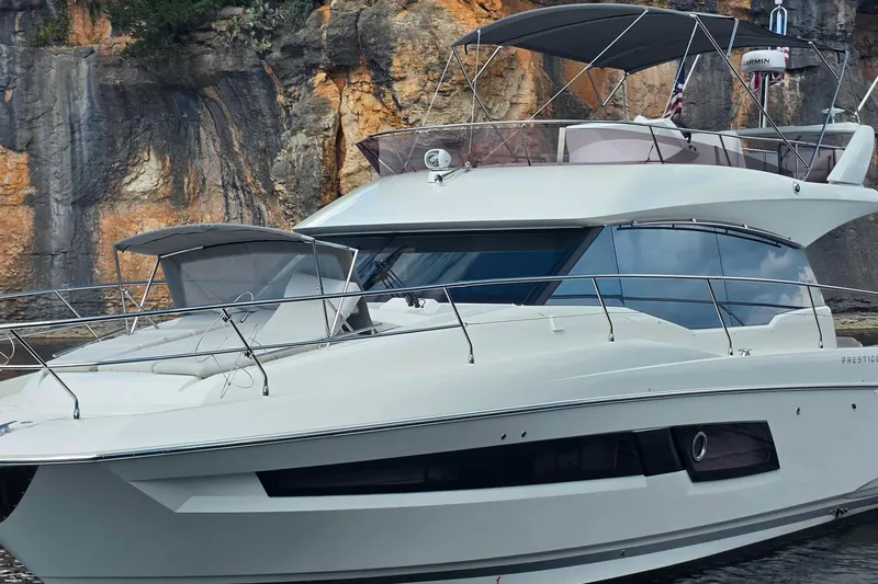 Im Your Huckelberry Yacht Photos Pics 2024 Prestige 460 yacht docked near rocky cliffs, showcasing sleek design and modern features.