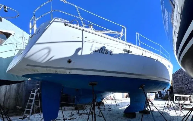 Lotus II Yacht Photos Pics 2007 Beneteau Oceanis 46 sailboat on stands, white hull, blue keel, clear sky background.