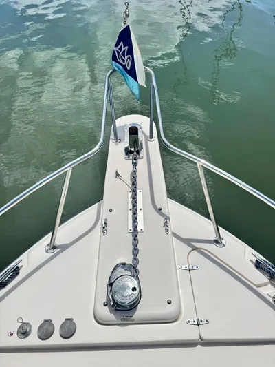  Yacht Photos Pics 2022 Grady-White Express 330 boat bow with anchor chain and flag on calm water.