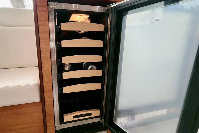 2024 Refit Yacht Photos Pics Wine cooler inside 2011 Hatteras 60 Motor Yacht, featuring wooden shelves and sleek design.