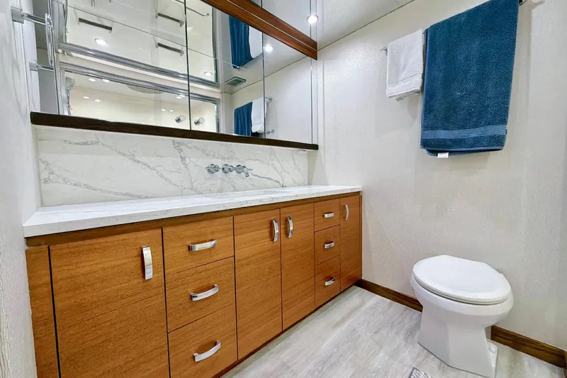 2024 Refit Yacht Photos Pics Luxurious bathroom in 2011 Hatteras 60 Motor Yacht with wooden cabinetry and marble accents.