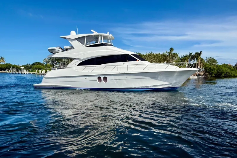 2024 Refit Yacht Photos Pics 2011 Hatteras 60 Motor Yacht cruising on a sunny day, surrounded by lush greenery.