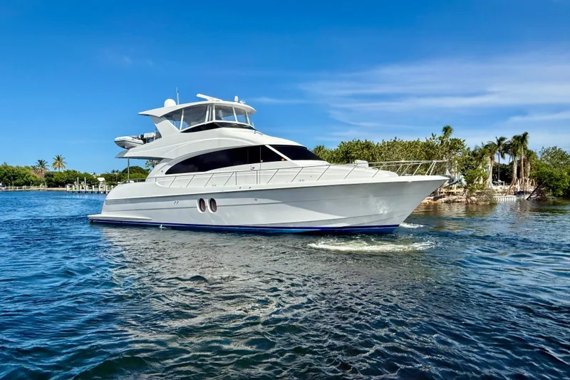 2024 Refit Yacht Photos Pics 2011 Hatteras 60 Motor Yacht cruising on a sunny day, surrounded by lush greenery.