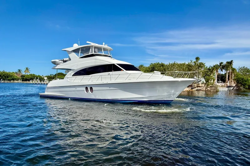 2024 Refit Yacht Photos Pics 2011 Hatteras 60 Motor Yacht cruising on a sunny day, surrounded by lush greenery.