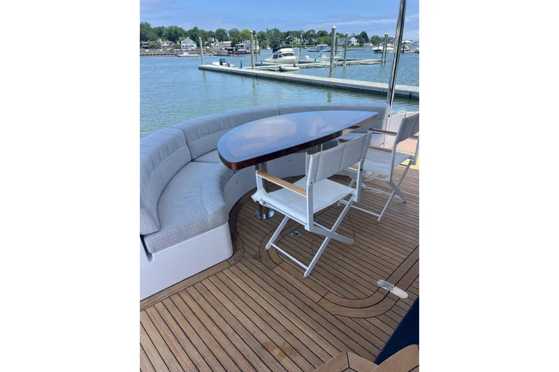 2024 Refit Yacht Photos Pics Luxury 2011 Hatteras yacht deck with seating, table, and scenic marina view.