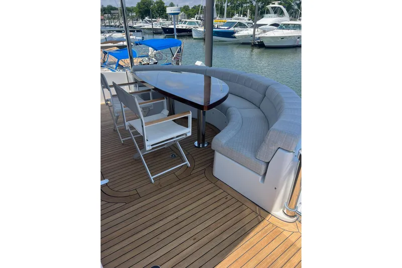 2024 Refit Yacht Photos Pics Luxury yacht deck with curved seating and table, Hatteras 2011, docked at marina.