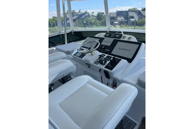 2024 Refit Yacht Photos Pics 2011 Hatteras yacht helm with Garmin navigation, white seating, and modern controls.