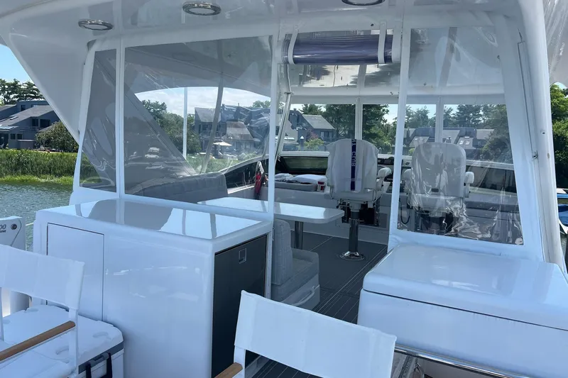 2024 Refit Yacht Photos Pics Luxurious 2011 Hatteras yacht interior with seating and clear enclosures, docked near waterfront homes.