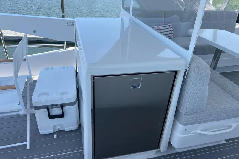 2024 Refit Yacht Photos Pics 2011 Hatteras yacht interior with seating, cooler, and mini fridge on deck.