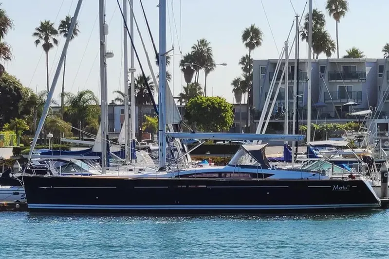 Motu Yacht Photos Pics 2013 Jeanneau 57 yacht docked in a marina with palm trees in the background.