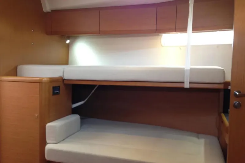 Motu Yacht Photos Pics Interior of 2013 Jeanneau 57 yacht with wooden bunk beds and storage cabinets.