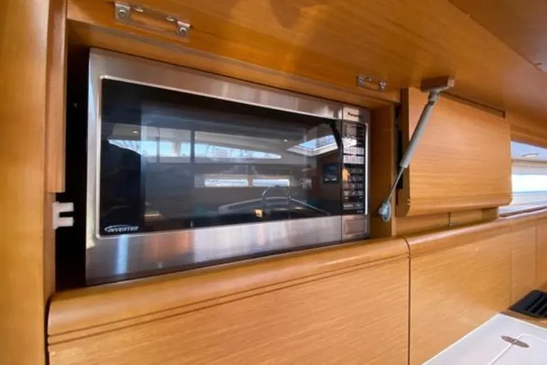Motu Yacht Photos Pics Microwave in 2013 Jeanneau 57 yacht kitchen, featuring sleek wooden cabinetry.