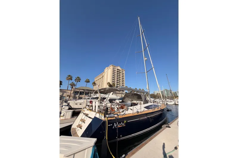 Motu Yacht Photos Pics 2013 Jeanneau 57 yacht docked at marina with clear blue sky.