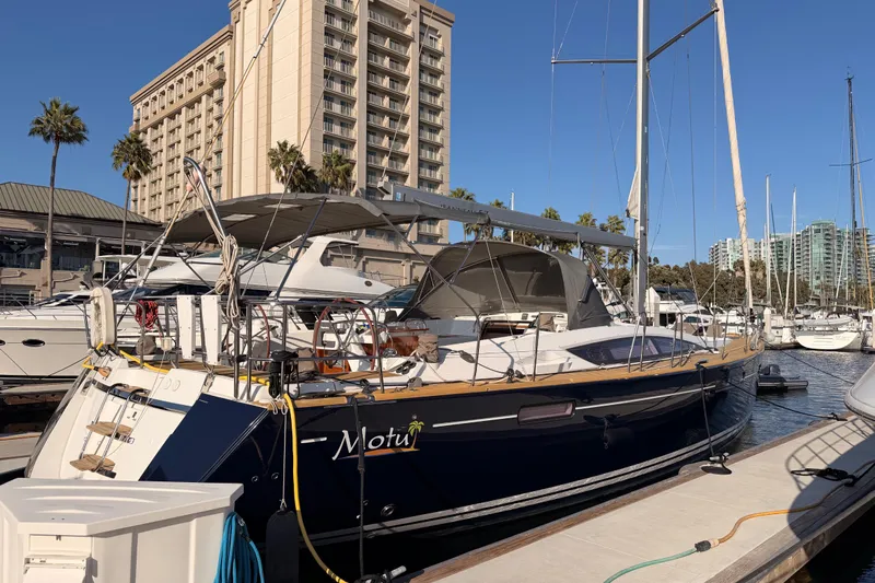 Motu Yacht Photos Pics 2013 Jeanneau 57 yacht docked at marina with cityscape background.