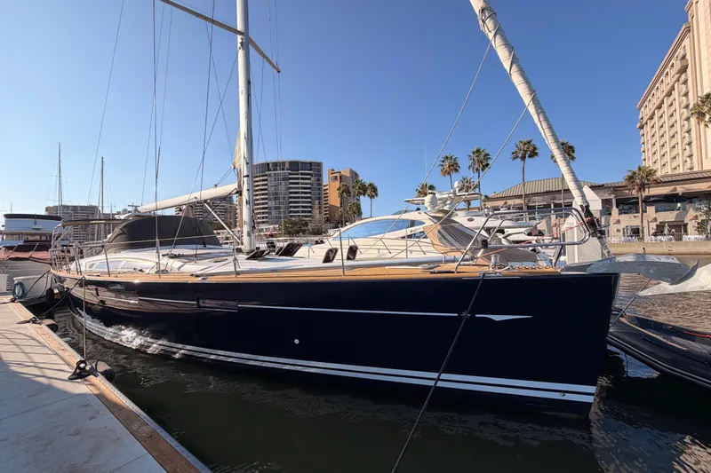 Motu Yacht Photos Pics 2013 Jeanneau 57 yacht docked in a marina with palm trees and buildings.