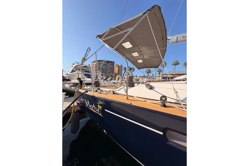 Motu Yacht Photos Pics 2013 Jeanneau 57 sailboat docked, featuring a sunshade and sleek design.