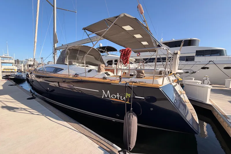 Motu Yacht Photos Pics 2013 Jeanneau 57 yacht docked at marina under clear blue sky.