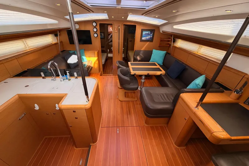 Motu Yacht Photos Pics Luxurious interior of a 2013 Jeanneau 57 yacht with modern furnishings and wood finish.