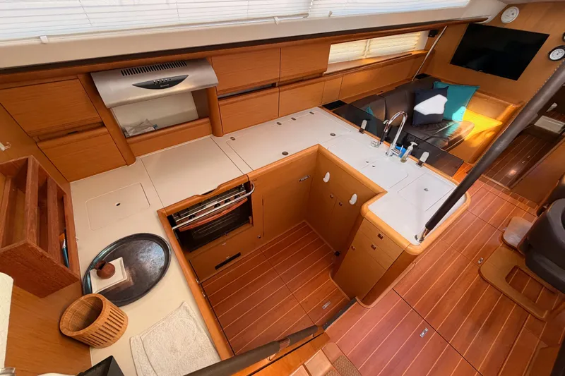 Motu Yacht Photos Pics Luxurious interior of a 2013 Jeanneau 57 yacht featuring a modern kitchen and seating area.