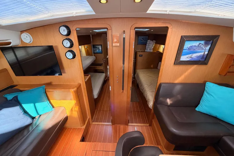 Motu Yacht Photos Pics Interior of 2013 Jeanneau 57 yacht with cozy seating and elegant wood finish.