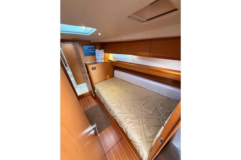 Motu Yacht Photos Pics Cozy cabin interior of 2013 Jeanneau 57 yacht with wooden finishes and comfortable bedding.