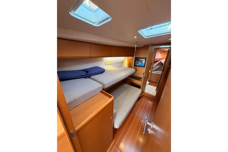 Motu Yacht Photos Pics Interior of 2013 Jeanneau 57 yacht with cozy bunk beds and wooden finish.
