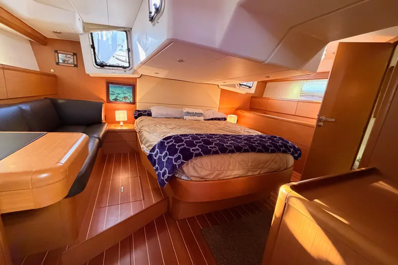 Motu Yacht Photos Pics Luxurious interior of 2013 Jeanneau 57 yacht with cozy bed and elegant wood finish.