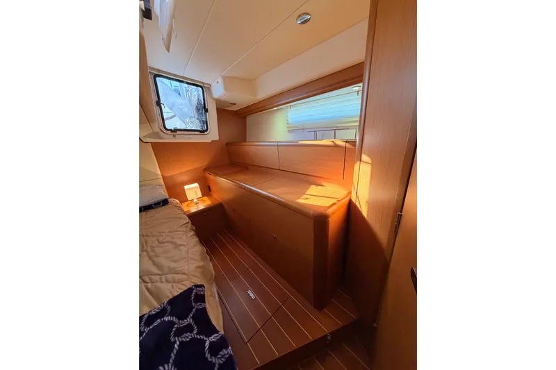 Motu Yacht Photos Pics Interior of 2013 Jeanneau 57 yacht cabin with wooden furnishings and cozy lighting.