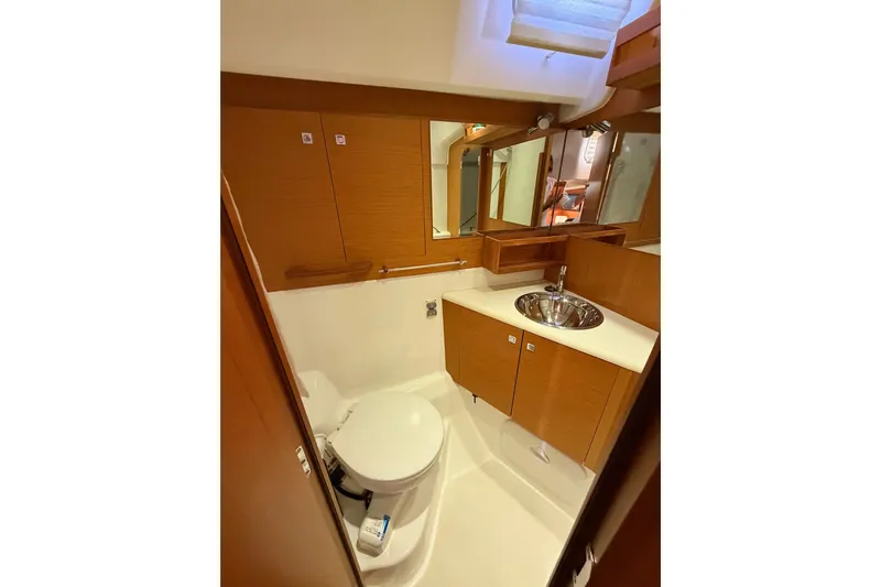 Motu Yacht Photos Pics 2013 Jeanneau 57 yacht bathroom with wooden cabinetry and stainless steel sink.