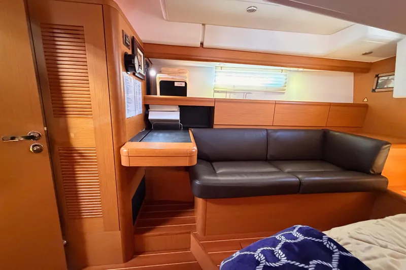 Motu Yacht Photos Pics Interior of 2013 Jeanneau 57 yacht with wooden finish and black leather seating.