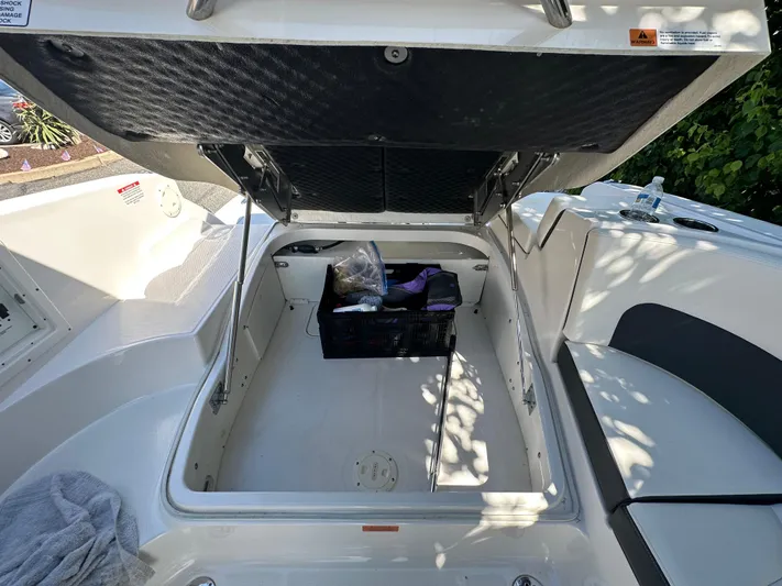  Yacht Photos Pics 2023 Chaparral 270 OSX boat storage compartment with open hatch and stored items.