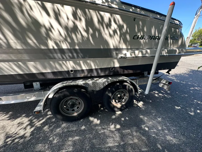  Yacht Photos Pics 2023 Chaparral 270 OSX boat on a trailer, parked in a shaded area.