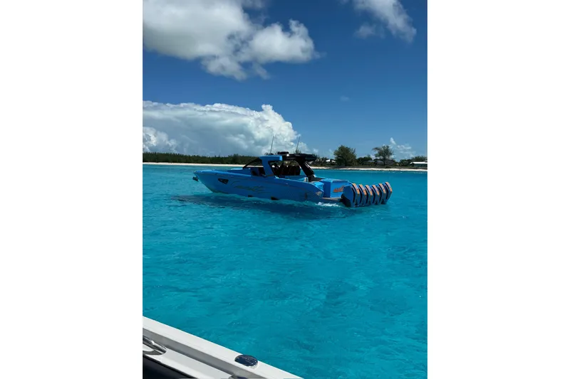  Yacht Photos Pics 2025 Cigarette 52 Thunder boat on clear blue water under a partly cloudy sky.