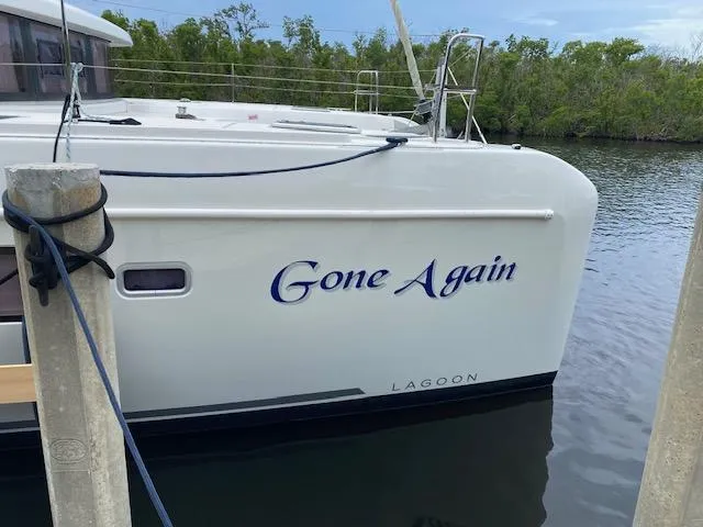 Gone Again Yacht Photos Pics 2019 Lagoon 42 catamaran named "Gone Again" docked by lush greenery.