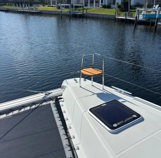 Gone Again Yacht Photos Pics 2019 Lagoon 42 catamaran deck with seating, docked by calm waters.