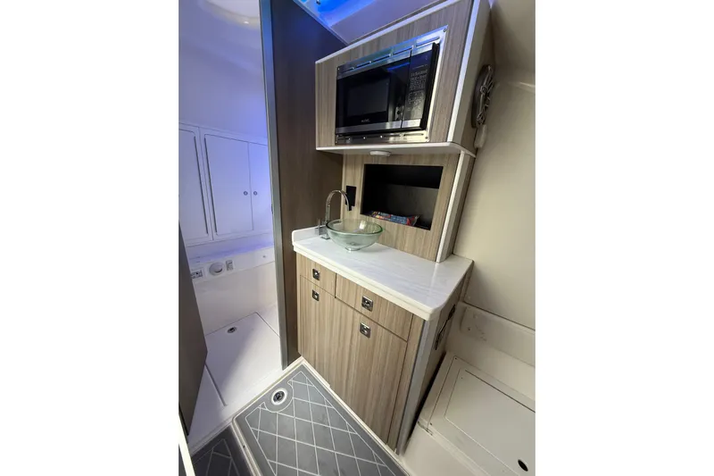  Yacht Photos Pics 2021 Fountain 43 NX boat interior with modern kitchenette, featuring sink and microwave.